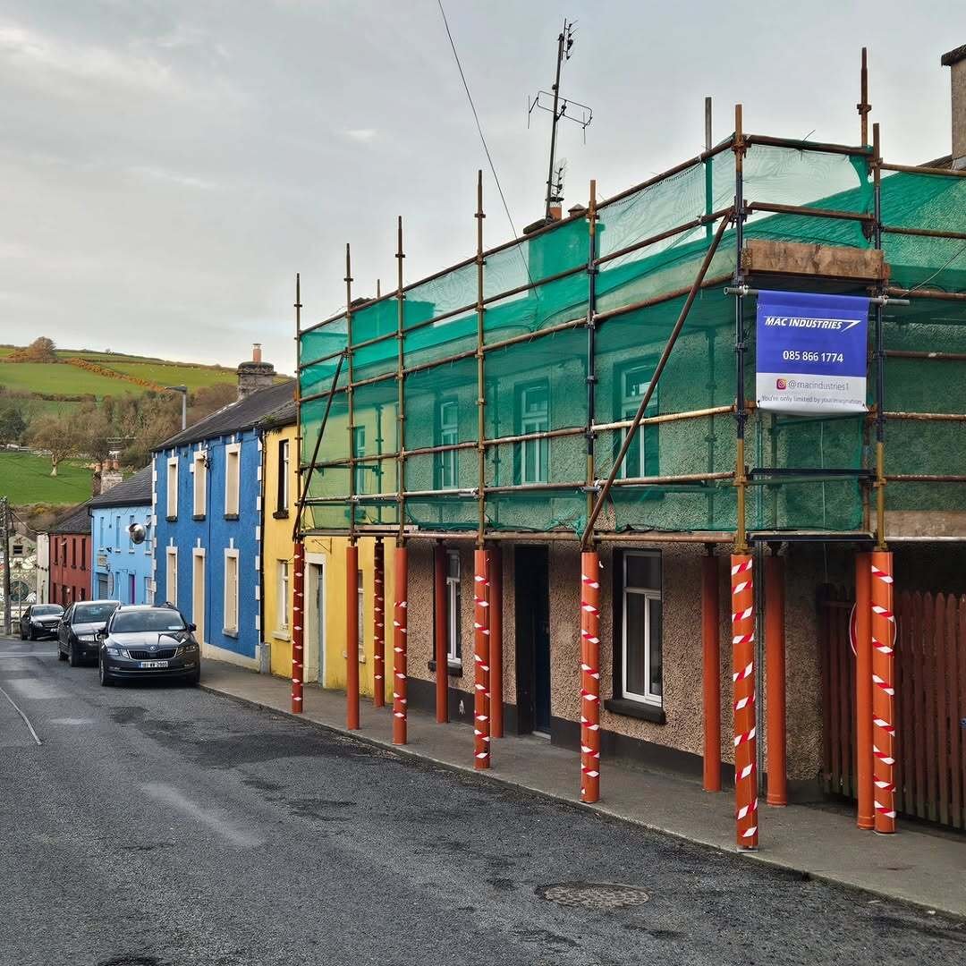 MacIndustries scaffolding with green safety netting and company banner on a terraced house on Barton Street, Wicklow