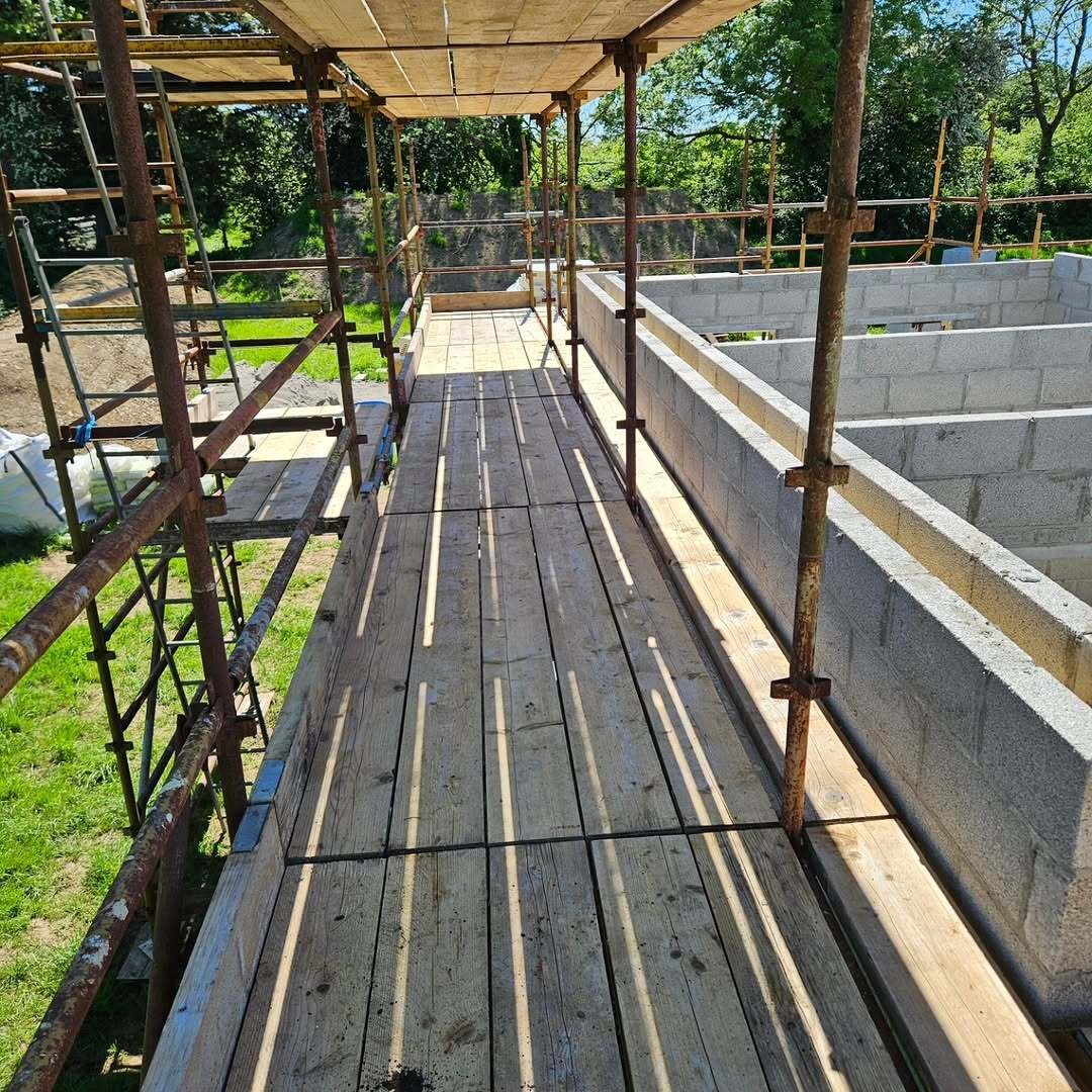 Scaffold platform beside new blockwork walls with excavated ground and trees beyond in Kiltale
