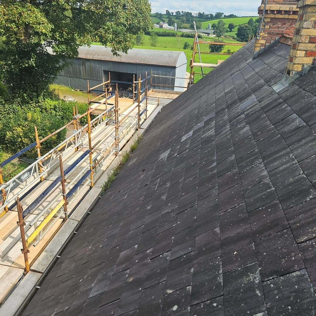 Elevated view of slate roof works with scaffolding and rural landscape beyond