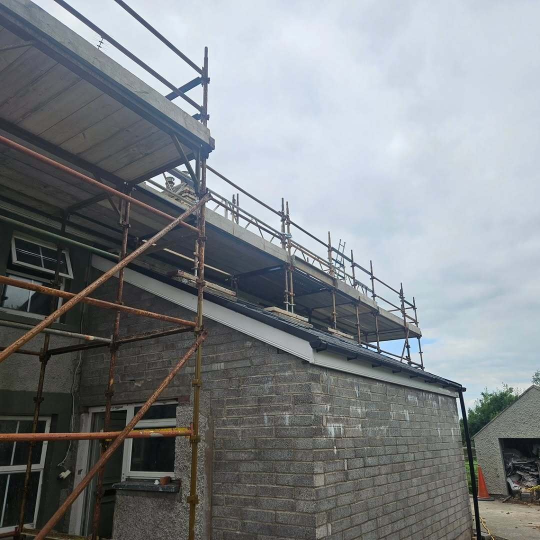 Scaffolding around a grey brick residential building during exterior wrap works