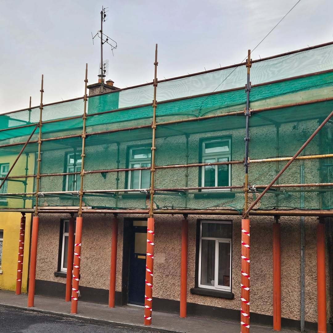 Front elevation of a pebbledash terraced house on Barton Street wrapped in scaffolding with green mesh